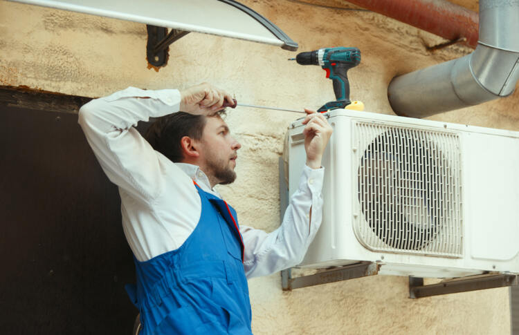 Image Of A Man Fixing An Aircon